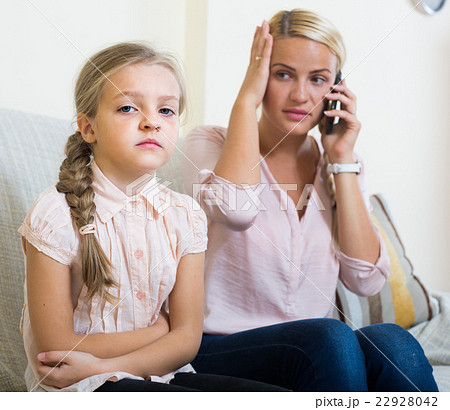 Worried mother calling doctor for daughter with abdominal pains Worried mother calling doctor for daughter with abdominal pains 22928042