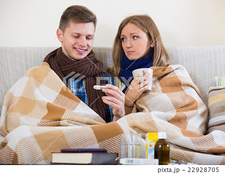 Sick couple under blanket checking fever 22928705