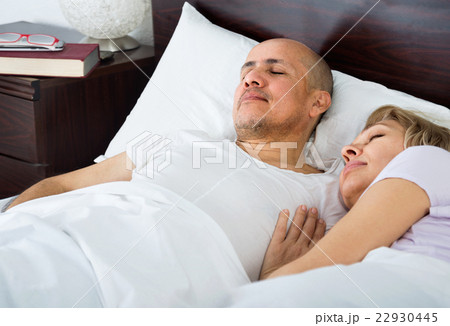 Portrait of ordinary mature couple napping in bed 22930445