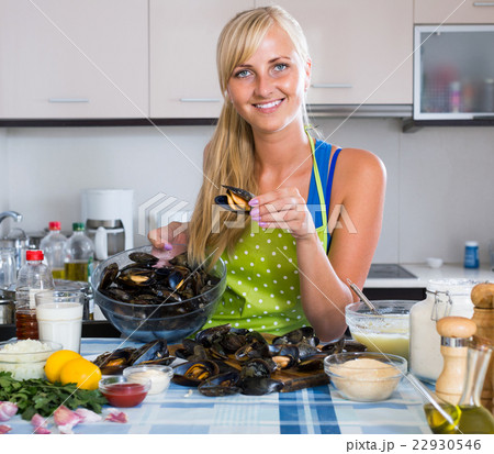 woman cooking marinade for tasty mussels at kitchen table 22930546