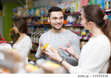 customers standing near shelves with canned goods at shop 22930936