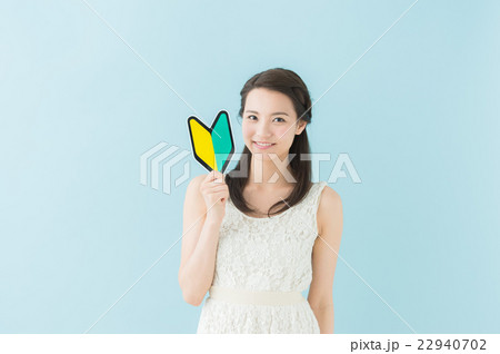 初心者マークを持つ女性（青背景） 22940702