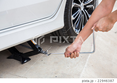 Hand lifting a car with spanner jack-screw Hand lifting a car with spanner jack-screw 22946387
