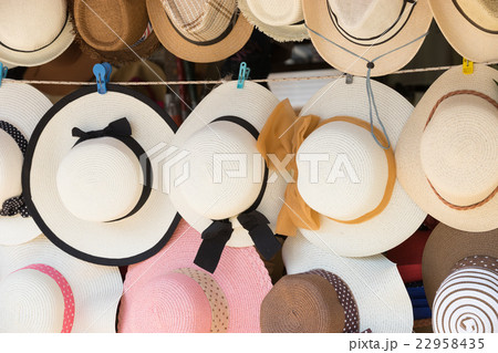Straw hats for sale, hanging on a wall.. 22958435