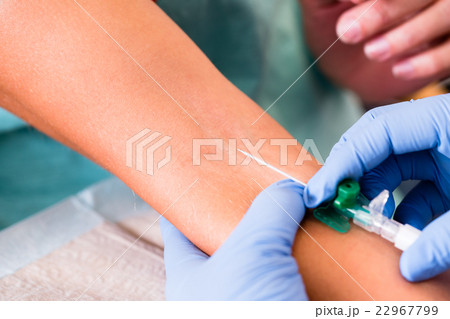 Physician or nurse taking blood sample of woman 22967799