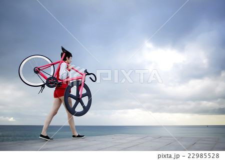 Young girl stroll with bicycle at seashore Young girl stroll with bicycle at seashore 22985528