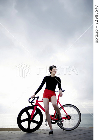 Stylish cyclist female standing against the sky Stylish cyclist female standing against the sky 22985547