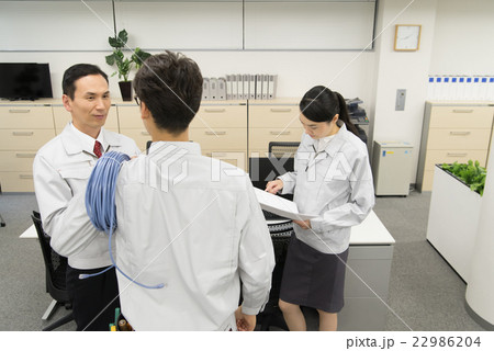 図面を見て打ち合わせする通信技術者 22986204