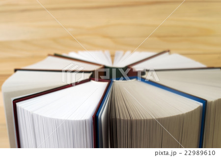 Open book, stack of hardback books on wooden table 22989610