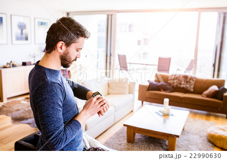 Man working from home using smart watch, living Man working from home using smart watch, living 22990630