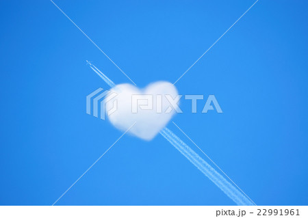 ハートの形をした雲と飛行機雲の写真素材