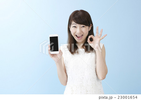 スマホを片手に笑顔の女性ブルーバック スマホを片手に笑顔の女性ブルーバック 23001654