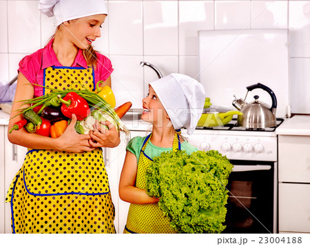 Children little girl cooking vegetables at kitchen 23004188