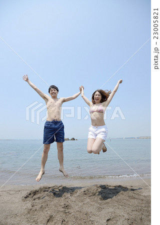 海でジャンプする若いカップルの写真素材