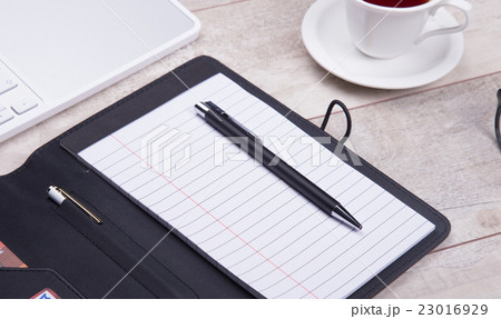 Blank notepad with pen on office wooden table Blank notepad with pen on office wooden table 23016929