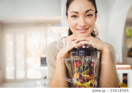 Portrait of happy woman preparing fruit juice Portrait of happy woman preparing fruit juice 23018564