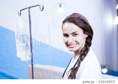 Portrait of female doctor carrying saline stand 23018857