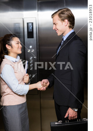 Businessman shaking hands with businesswoman in elevator Businessman shaking hands with businesswoman in elevator 23018953