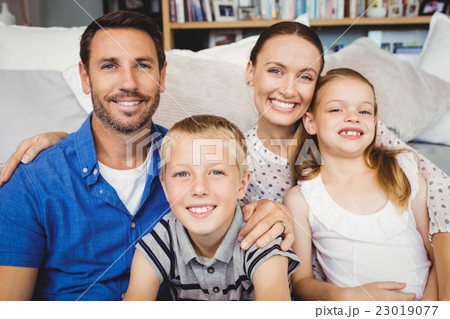 Portrait of happy family sitting by sofa Portrait of happy family sitting by sofa 23019077