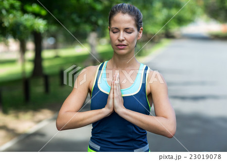 Sportswoman meditating with hands joined 23019078