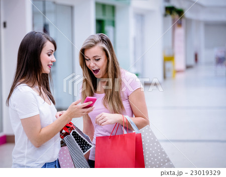 Two beautiful women looking at phone 23019329