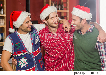 Friends with Christmas hats smiling at each other Friends with Christmas hats smiling at each other 23019562