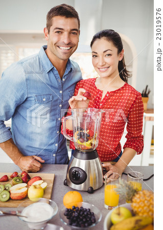 Portrait of smiling couple preparing fruit juice Portrait of smiling couple preparing fruit juice 23019576