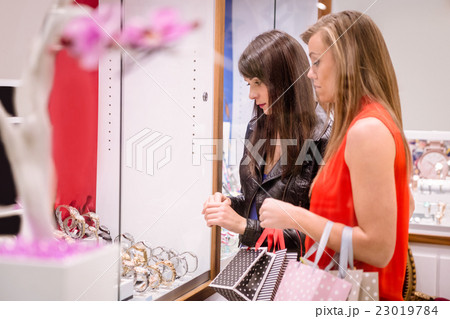 Two beautiful women looking at a display in shop Two beautiful women looking at a display in shop 23019784