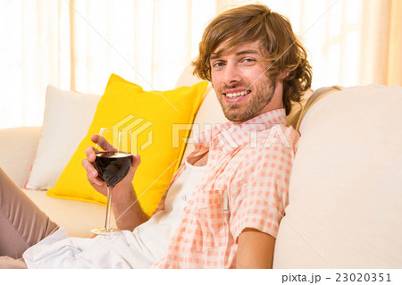 Handsome man enjoying a glass of wine on the couch Handsome man enjoying a glass of wine on the couch 23020351