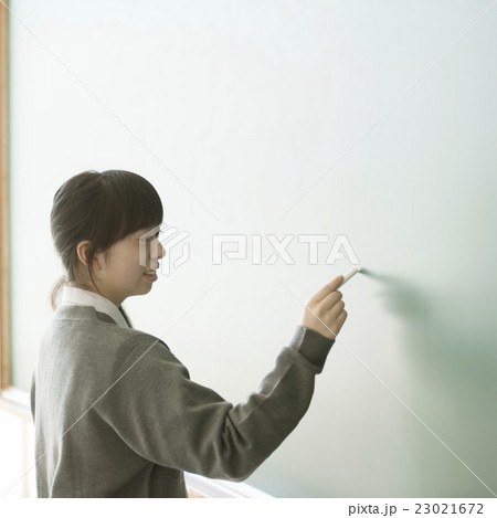 黒板に文字を書く女子学生の写真素材