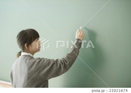 黒板に文字を書く女子学生の写真素材