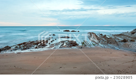 Twilight ocean coast with ribbed stratiform rock. 23028905