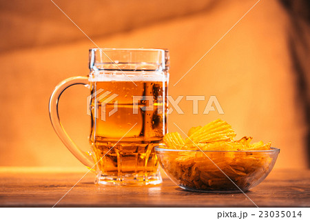beer mug with bowl of potato chips on wooden table 23035014