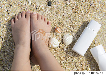 日焼け止めと海と子供の足の写真素材