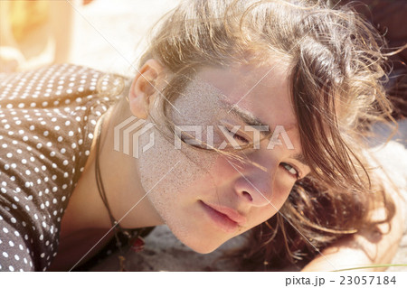 woman laying on the beach with sand in her face woman laying on the beach with sand in her face 23057184