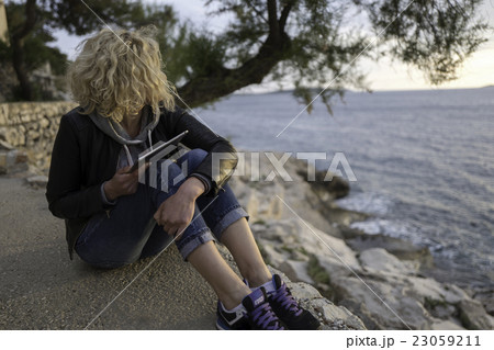 Beautiful girl seating on the stones near of sea  23059211