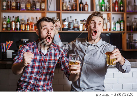 Young people with beer watching football in a bar 23071820