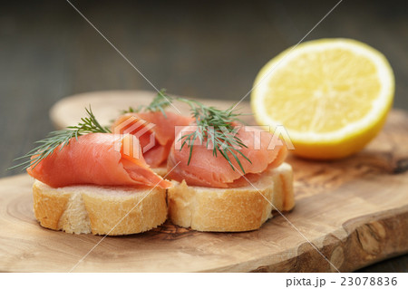 baguette slices with curred salmon and dill on wood table baguette slices with curred salmon and dill on wood table 23078836