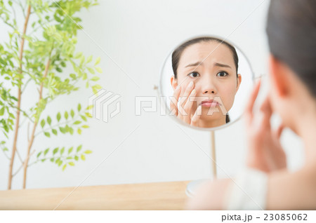 鏡を見る女性（目元ケア　20代) 23085062