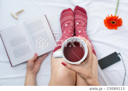 Woman reading a book and having cup of tea Woman reading a book and having cup of tea 23089113