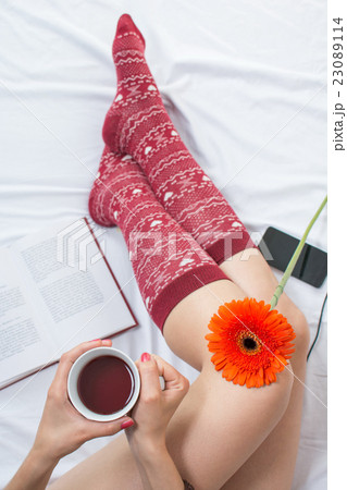 Woman holding a cup of tea in bed Woman holding a cup of tea in bed 23089114