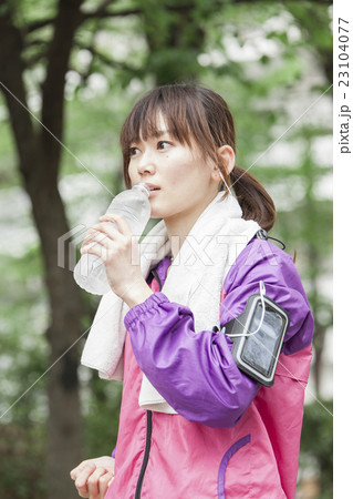 スマホで音楽を聴きながらジョギングする女性 スマホで音楽を聴きながらジョギングする女性 23104077