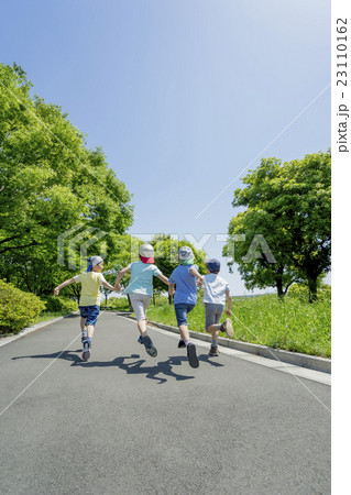 新緑の公園で遊ぶ小学生たちの後ろ姿 23110162