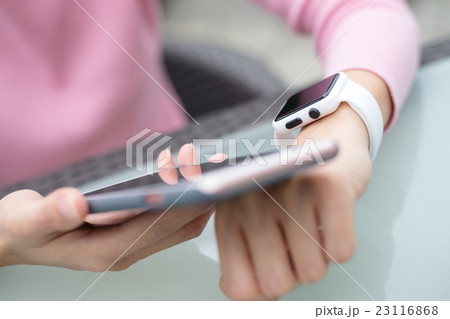 Woman using cellphone to connect with smart watch Woman using cellphone to connect with smart watch 23116868