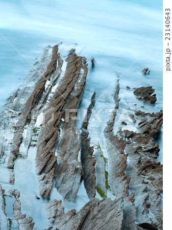 Twilight ocean coast with ribbed stratiform rock. 23140643