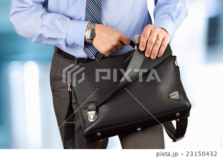 Man holding and opening a leather briefcase Man holding and opening a leather briefcase 23150432