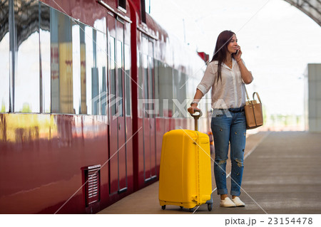 Young woman with luggage talking by cellphone at a 23154478