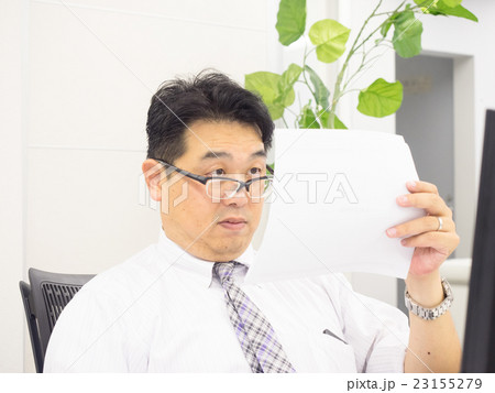 メガネをずらして書類を見るビジネスマン メガネをずらして書類を見るビジネスマン 23155279