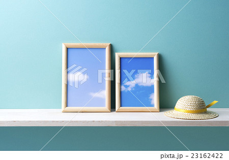 青い背景と写真立てと麦わら帽子のオブジェの写真素材 [23162422] - PIXTA