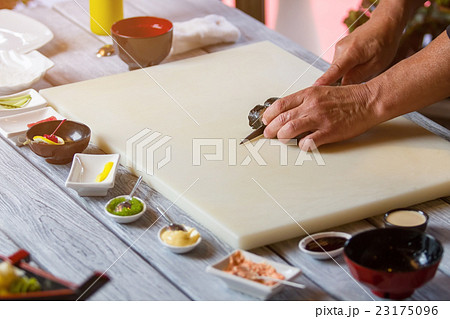 Hands with knife cutting sushi. Hands with knife cutting sushi. 23175096